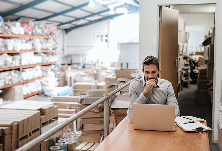 E_Commerce Multi-Channel-Ansatz, der Telefonsupport, Self-Service-Optionen, Helpdesk-Systeme, E-Mail, Live-Chat und soziale Medien Mann sitzt am Laptop in einem Lageraum